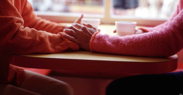 Two women at cafe table holding hands